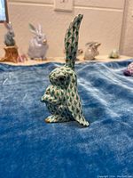 Right side view of the rabbit figurine showing green fishnet pattern and gold accents