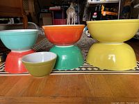 Overview of the seven bowls stacked in pairs and one small bowl front left, showing the various colors and sizes.