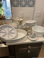 Full set of white ceramic kitchenware including casserole, pitchers, loaf pans, and demitasse set on counter