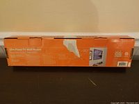Photo of damaged orange box showing the slim fixed TV wall mount packaging and size compatibility (24-90 inches).