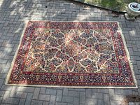 Full view of the Arakstan area rug laid flat on a brick patio under natural light showing complete floral pattern and border