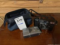 Photo showing both cameras and carrying case on a wooden surface.