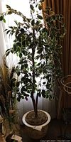 Full view of faux tree with variegated green and cream leaves in ceramic planter near window with curtains.