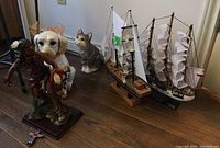 View of all items showing two model boats and multiple figurines including dog, cat, Native American horseman, and totem.
