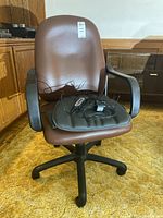Front view showing the brown leather office chair with a Dr Scholls back massager placed on the seat with attached remote control and cords.