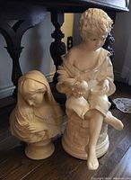 Sculpture of young child sitting with bird on round base, showing detailed face, hair, and clothing