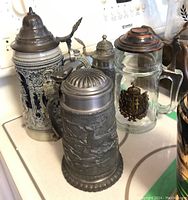 Four beer steins displayed on a kitchen counter with stove in background