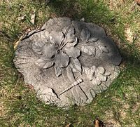 Concrete stepping stone with hibiscus flower and dragonfly design on grass