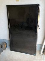 Full front view of the TV leaning against a wall showing the entire 55-inch screen and black frame.