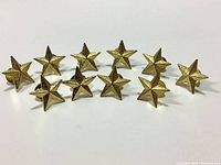 Front view of 10 gold star pin badges showing 3D textured stars