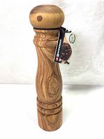 Front view of the olive wood pepper mill grinder showing its shape, wood grain, and Swissmar branded tag