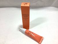 Sealed orange tube and matching orange box of Shiseido WASO Eye Opening Essence on neutral background
