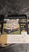 Box of Classic Accessories Travel 4-Sided Golf Cart Enclosure showing product image of beige enclosure on golf cart.