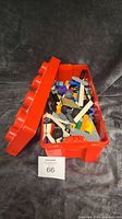 Red Lego carrying case open with varied Lego bricks and pieces inside on a gray background