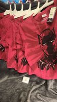 Six red Black Panther T-shirts hanging on hangers, showing Marvel tag and design.