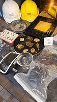 Photo showing CN Rail white and yellow hard hats, 5x7 shadow frame with gold-black design, Scentsy wax melts box, small pins/clips on black oval board, and silver-tone trays and coasters