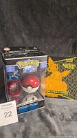 Front and side views of sealed Pokemon Catch 'N' Return Pokeball featuring Swampert and Laggon figures with included Pokemon Shining Fates Player's Guide book beside it.