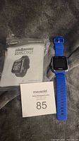 Blue Vtech Kidizoom Smart Watch DX2 with charger and Parent's Guide on gray surface, includes MaxSold lot card.