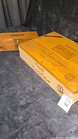 Two wooden wine boxes placed on dark fabric, Groth box larger in front, Tignanello smaller behind