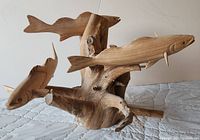 Front and side view of the wood sculpture showing three carved fish attached to a natural wood base.