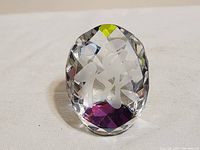 Front view of the clear faceted crystal paperweight showing the white etched Asian character inside and purple base tint.