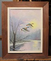 Frontal view of the painting depicting flying ducks over a river at sunrise or sunset in a wooden frame.