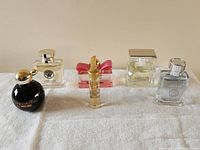 Photo showing six perfume bottles on a cloth surface: Moschino Cheap And Chic, Versace, Salvatore Ferragamo Signorina In Fiore, Vanitas, and two Versace Euroitalia miniatures.