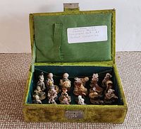 Photo showing the complete set of Red Rose Tea Nursery Rhyme figurines in green velvet lined box with hinged lid and a label inside the lid.