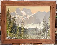 Framed oil painting of Rocky Mountain landscape with pine trees and mountains under an orange sky, mounted on an easel.