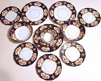 Overview photo showing 11 pieces of Royal Albert Heirloom Derby serving ware arranged on a flat surface to display front pattern and variation in size.