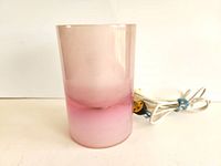 Front view of vintage acrylic cylinder table lamp showing gradient pink to cream colors, cord visible beside it.