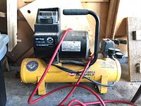 Full view of Campbell Hausfeld air compressor with red hose coiled around it, showing overall condition and structure.