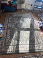 Full view of the large area rug on hardwood floor with visible shadow from the window.