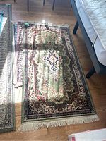 Top view of medium size area rugs overlapping, green central rug with ornamental floral design visible