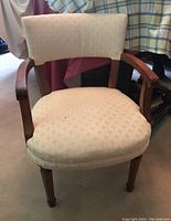 Front view of the wood framed armchair with upholstered seat and back in light cream fabric.