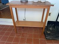Front view of the wood console table showing four legs, top surface, and lower shelf