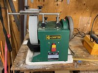Full side view of green Craftex wet grinder showing 10-inch grinding wheel and control switches on wooden workbench.