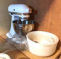 KitchenAid Classic stand mixer with stainless steel bowl, pouring shield, and attachments on wooden surface