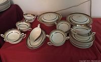 Overview of dinnerware items on red tablecloth showing bowls, saucers, servers and gravy boat