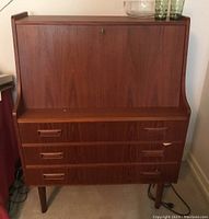 Front view of closed drop-front desk showing teak finish and tapered legs