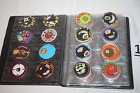 View of a binder page with 16 colorful milk caps (POGs) featuring numbers, pool balls, and other designs.