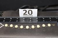 Bracelet measured with ruler showing length approximately 7.5 inches with carved scarab beads and metal chain links.