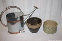 Metal Vigoro watering can with silver body and copper bands, large 23 inch size, alongside two ceramic pots on white background
