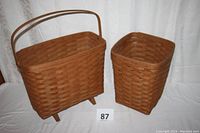 Two Longaberger baskets side-by-side, large basket with feet and handle on left, medium basket on right