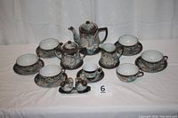 Full set displayed, showing teapot, sugar bowl, creamer, six teacups with saucers, demitasse cup, and salt and pepper set on tray with dragon motifs.
