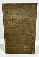 Front cover of the hardcover book showing textured brown cloth and faded gold embossed title and event details.
