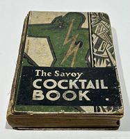 Front cover showing art deco green, black, and gold design with title 'The Savoy Cocktail Book' and signs of wear