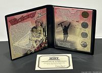 Display folder open showing left panel with Victory 5 cent collection history and image of soldier, right panel holding four commemorative coins dated 1943, 1944, 1945, and 2005, with soldier silhouette background and certificate of authenticity placed inside.