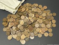 Loose collection of old Canadian and American pennies spread out on a black surface.