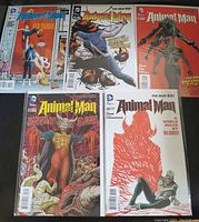 Top view of five Animal Man comic books, issues 20 to 24, arranged in two rows on a dark surface, showing colorful and detailed cover art for each issue.